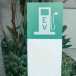 Odisha EV charging stations promotional graphic showing EV charger, electric car, temple backdrop, and state transport initiative